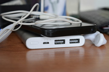 Silver power bank and a black phone are lying on the table