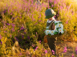 little boy playing in the park.
Boy with a basket in a flower field. Walk in the fresh air. Violet green.