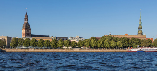 Fototapeta premium Sightseeings of Riga from the river Daugava. View of the Dome Cathedral, St. Peter's Church and the promenade.