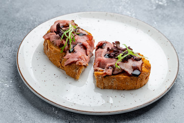 Bruschetta with roast beef on grey stone table