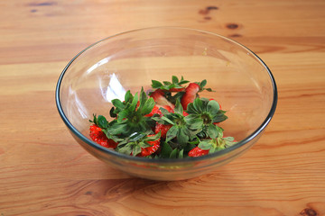 strawberry leaves from the green top part cut in a bowl - leftovers of a fruit salad recipe