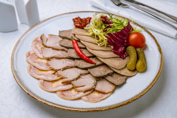 slicing of different meat on white table