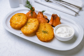 Fried potato pancakes with salmon and sour cream