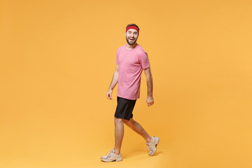 Fototapeta na wymiar Side view of funny young bearded fitness sporty guy sportsman in headband t-shirt spend weekend in home gym isolated on yellow background. Workout sport motivation lifestyle concept. Looking camera.
