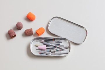 Set of professional manicure tools in a metal box on a gray table. A lot of used cutters, pushers, nail files .