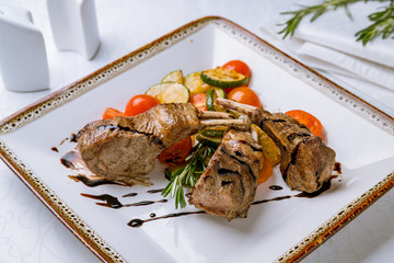 Rack of lamb with fried vegetables on white table