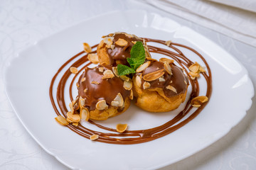 Profiteroles with chocolate sauce on white plate
