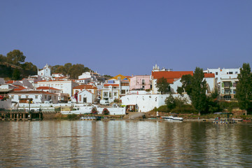 Fototapeta na wymiar Alcoutim, un pequeño pueblo de la región del Algarve en Portugal. Vista de su puerto deportivo y casas a orillas del río Guadiana desde la orilla española en Sanlúcar de Guadiana.