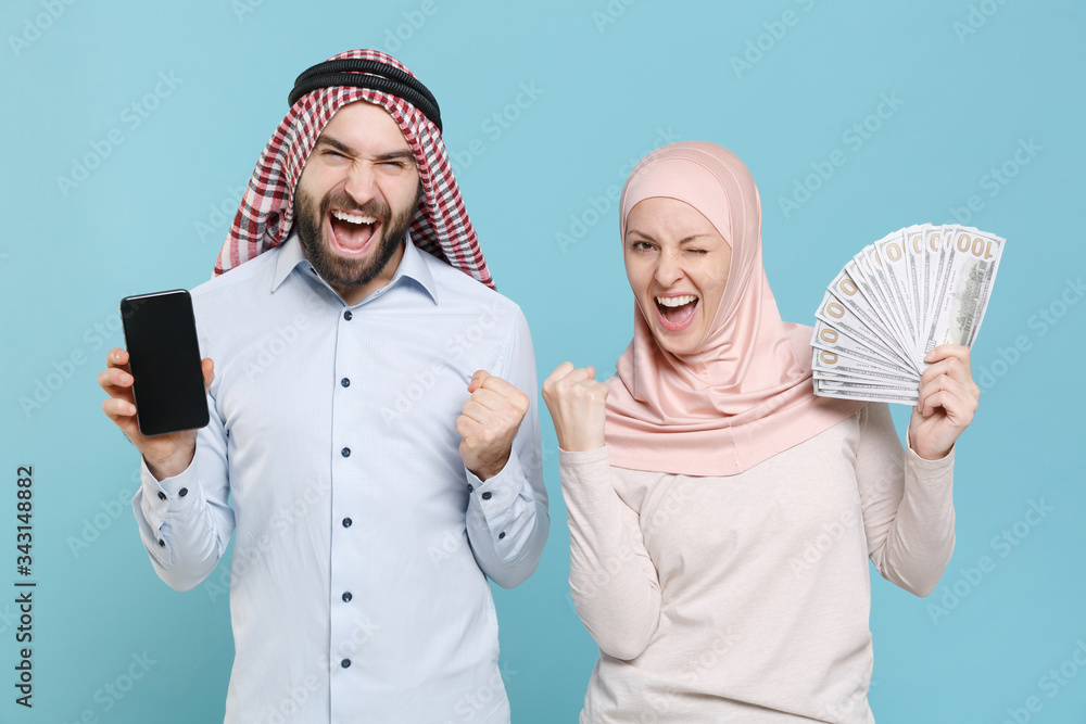 Wall mural couple friends arabian muslim man wonam in keffiyeh kafiya ring igal hijab clothes isolated on blue 