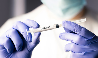 Covid 19 vaccine, immunity and medical treatment concept. Coronavirus syringe and needle. Doctor or nurse working in health care wearing a mask. Corona virus injection shot research. NCOV pandemic.