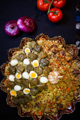 Traditional georgian dolma in grape leaves on black table with female hand