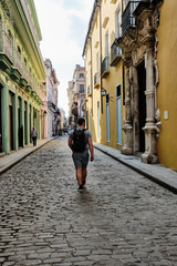 Fototapeta na wymiar Man with a backpack on walking away from the camera in Old Havana.
