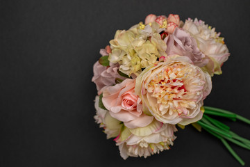 Bouquet of flowers. Delicate floral arrangement of peonies. The bride's bouquet. Artificial roses on a dark background. Decoration for the interior. Top view with copy space, flat lay.