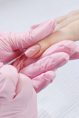 Woman in nail salon receiving manicure by beautician. Manicure process in beauty salon, close up. Close up of a woman hand with pink nail polish after the manicure.