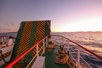 a car transportation ferry with ramp up in the sea on a sunrise