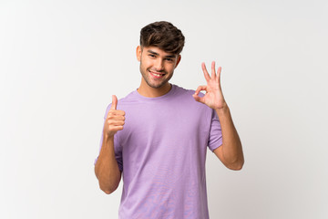 Young handsome man over isolated white background showing ok sign and thumb up gesture