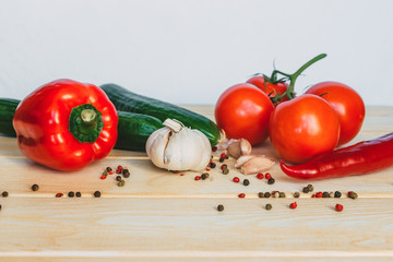 vegetables and spices lie on a light yellow wooden table. Vegetarian food, side view