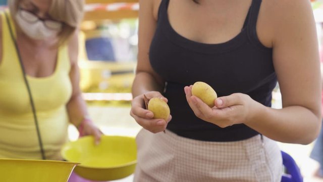 Young woman in mask picking potatoes at grocery store during pandemic
