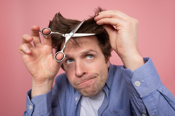 man trying to make a hairstyle by himself with scissors being on quarantine
