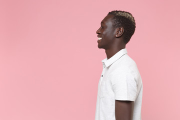 Side view of smiling young african american man guy in white polo shirt posing isolated on pastel...