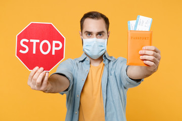 Young man in sterile face mask posing isolated on yellow background in studio. Epidemic pandemic...