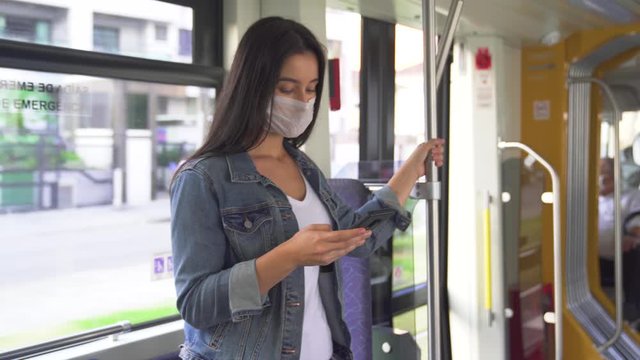 Young woman in protective medical face mask on a train subway car, pandemic coronavirus concept