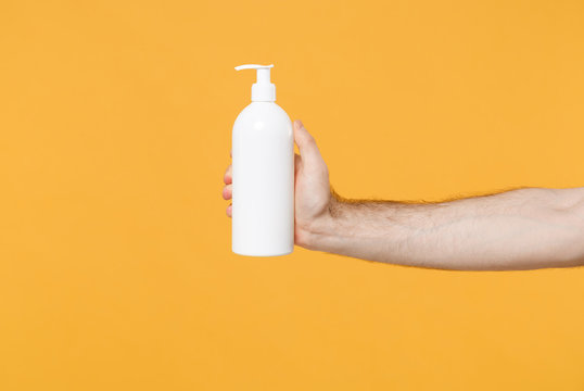 Close Up Cropped Photo Of Male Hold In Hand Bottle With Antibacterial Sanitizer Soap Isolated On Yellow Background. Epidemic Pandemic Coronavirus 2019-ncov Sars Covid-19 Flu Virus. Mock Up Copy Space.