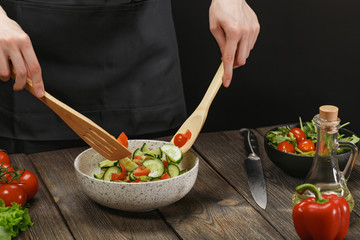 Woman mixing fresh healthy vegetable salad on wooden table. Female hands with copyspace.