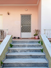 house entrance stairs to small terrace, white door and dark pink wall