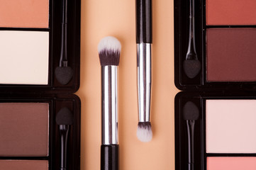 Cosmetic palette with brushes lies on a beige background.