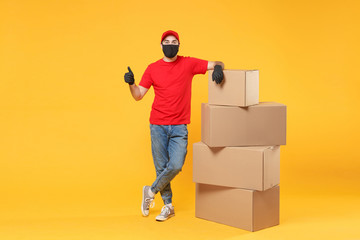 Delivery man employee in red cap blank t-shirt uniform face mask glove hold empty cardboard box...