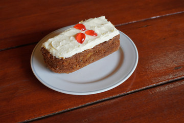 Carrot cake placed in a white ceramic dish on a wooden table, copy space