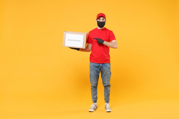 Delivery man employee in red cap blank t-shirt uniform face mask glove hold donations cardboard box isolated on yellow background studio Service quarantine pandemic coronavirus virus 2019-ncov concept