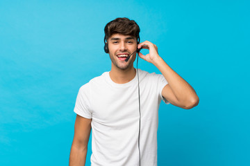Naklejka premium Young handsome man over isolated blue background working with headset