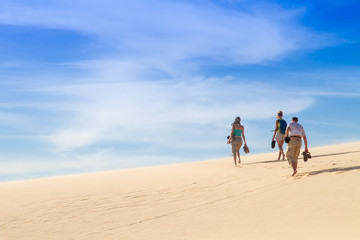 People walk along the sand dunes, view from the back, copy space.