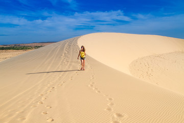 Woman walking along the crest of a dune, alone