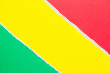 Yellow, green and red torn sheet of cardboard paper with diagonal border texture background. Copy...