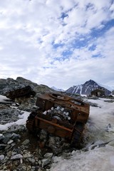 Rusty tank wreck in Antarctica, at Stonington Island, with east base, mountain and explorers in background