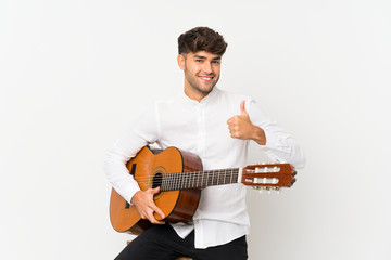 Obraz premium Young handsome man with guitar over isolated white background with thumbs up because something good has happened