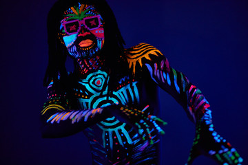 cheerful cool fashion dancer in fluorescent body art, african man move in dark neon space, fluorescence and luminescence concept