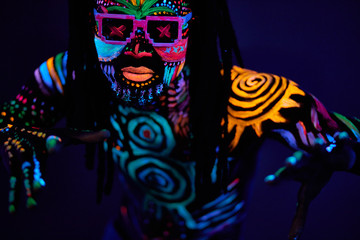 portrait of young unrecognizable man in sunglases with fluorescent prints on skin, cool handsome fashionable guy posing at camera