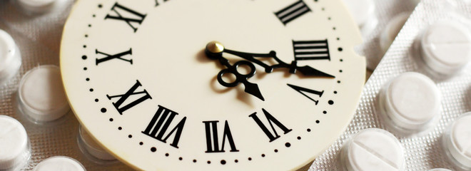 Watch with Roman numerals and white tablets, medicine, top view