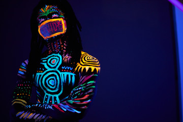 portrait of african male posing with COVID-19 inscription on mask, fluorescent prints glows on neon...