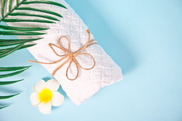 Care, beauty and spa concept. White towel and plumeria frangipani flower. Copy space. Top view.