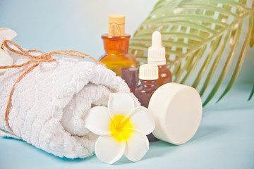 Obraz na płótnie Canvas Care, beauty and spa concept. Organic soap, small bottles with essential oils, white towel, palm leaf, plumeria frangipani flower.