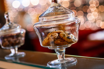 Decorative Glass jars with homemade cookies on a shop window. Warm natural light. Bokeh of lights in the background
