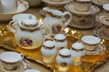 Luxury white ceramic tea set on a golden platter 
