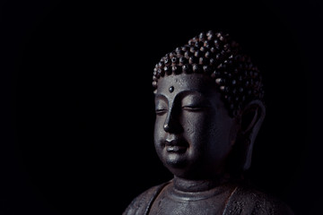 Meditating Buddha Statue isolated on black background. Copy space. 