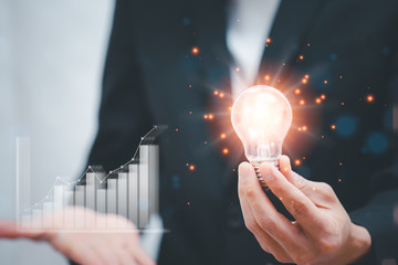 Businessman Catch the light bulb on blue background dark polygon digital network with using line...