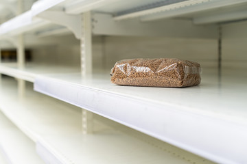 Shopping during virus outbreak. One packet of buckwheat on empty supermarket shelves. grocery store. pandemic. coronavirus. The concept of crisis and food shortages